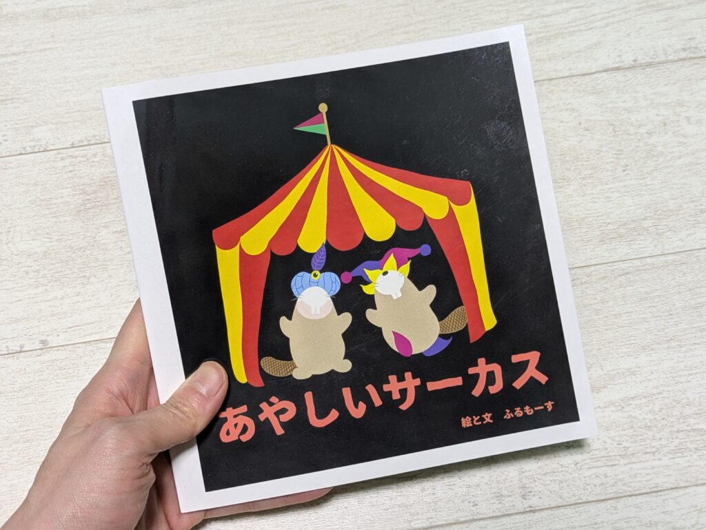 あやしいサーカスの絵本を持った手