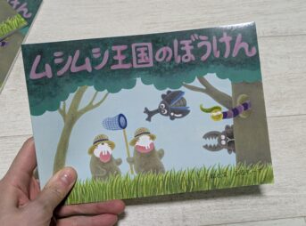 ムシムシ王国のぼうけん絵本を持った手