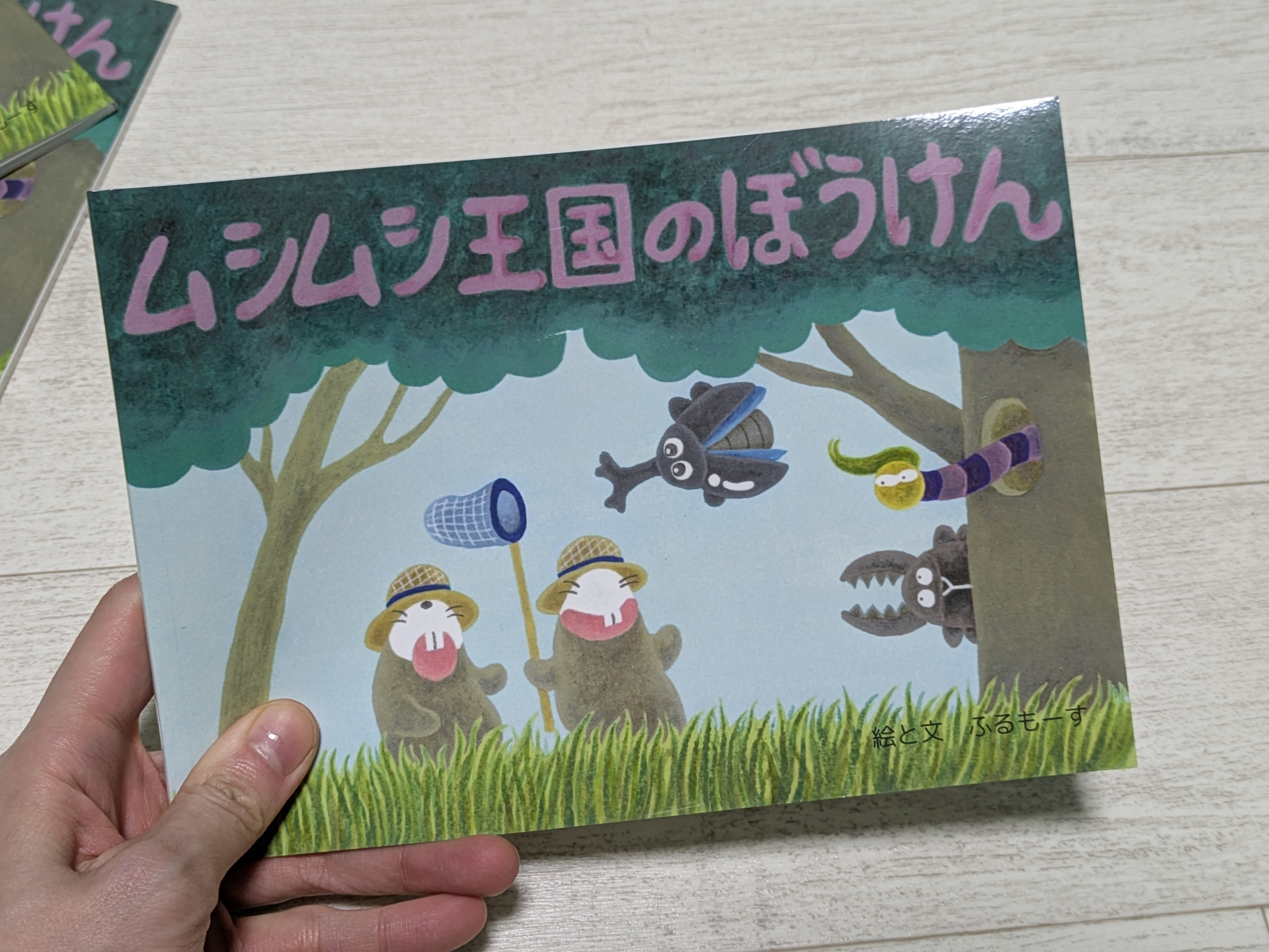 ムシムシ王国のぼうけん絵本を持った手